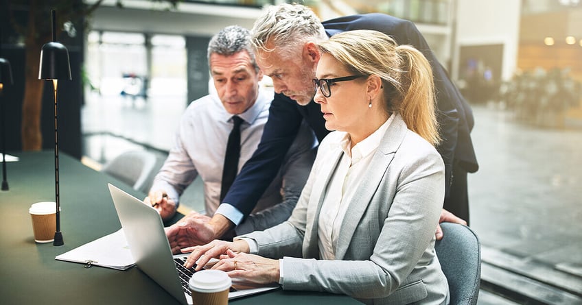 Three business managers review SEO changes on laptop